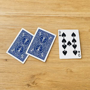 3 Card Monte magic trick - the three cards laid out on the table with the face card revealed