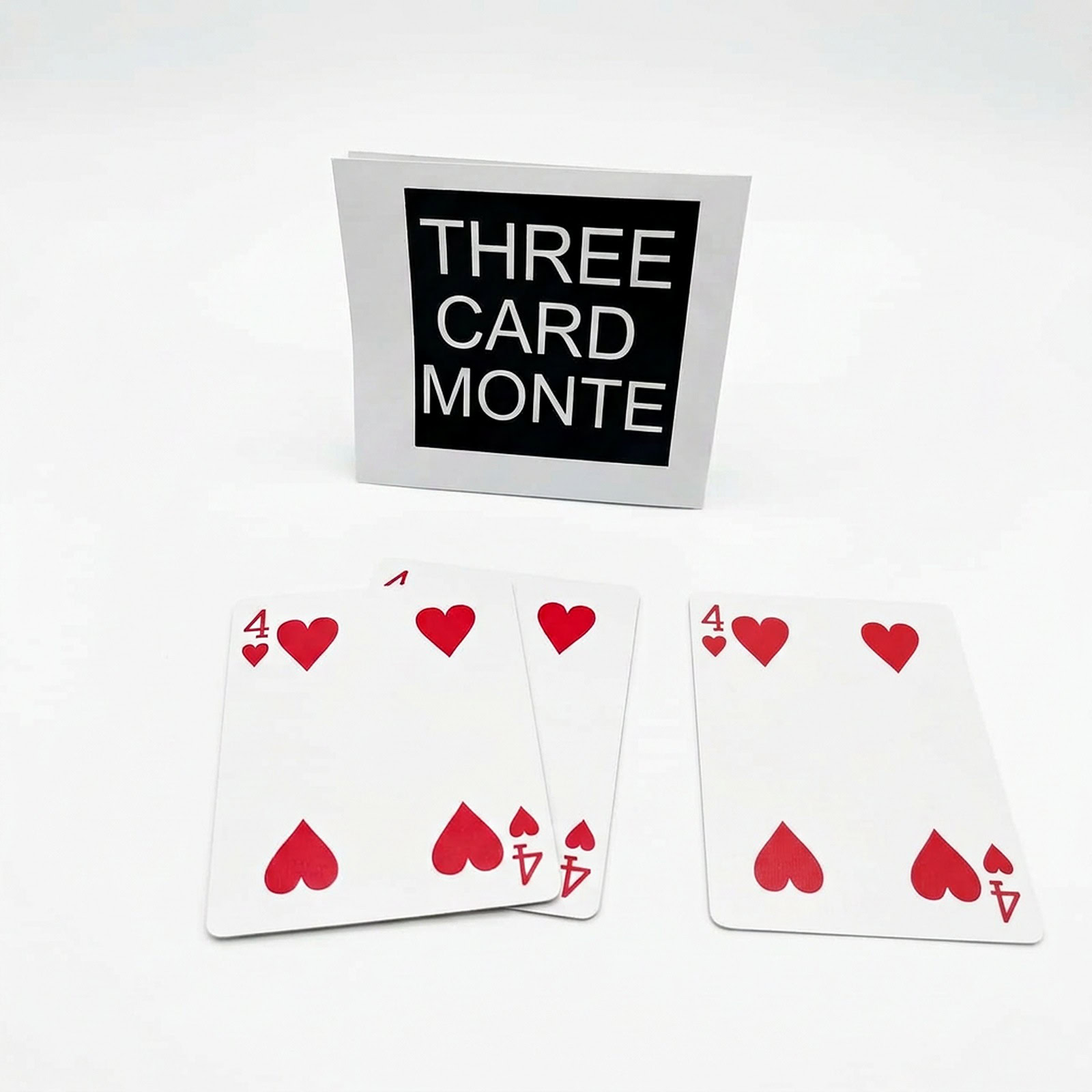 3 Card Monte magic trick - the ending of the routine with the three Four of Hearts cards left face up, two fanned together and one beside them