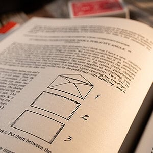 A magician's instructional book with diagrams on performing card tricks and illusions.