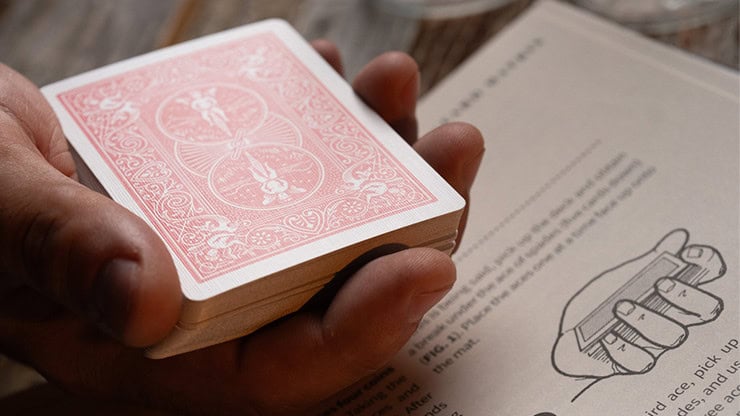 A deck of playing cards held in a person's hand on a wooden surface.