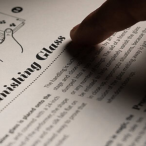 Close-up of a finger pointing at a diagram of a vanishing glass on a printed page.