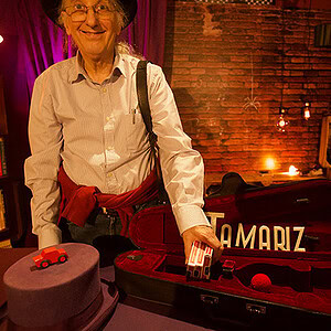 Woman performing magic with a small red car in a cozy bookstore setting.