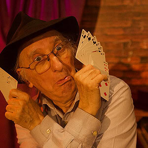 Juan Tamariz performing card magic with a playful expression at Dreamlandmagic.