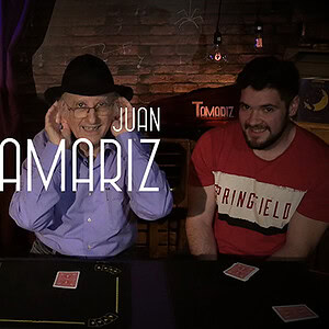 Juan Tamariz performing magic with two young assistants in a cozy shop setting.