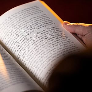 A person reading a book with warm lighting.
