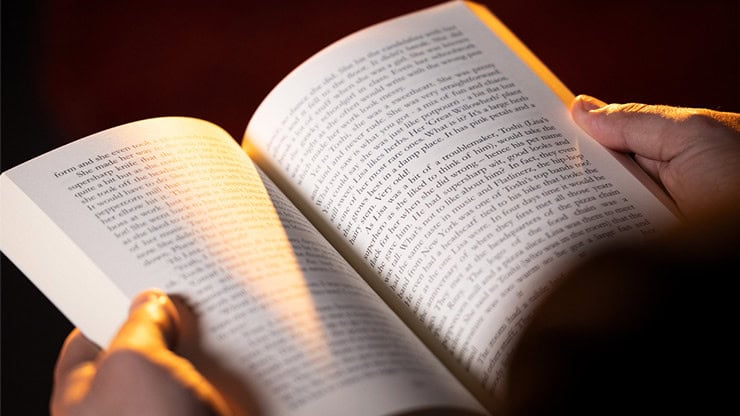 A person reading a book with warm lighting.