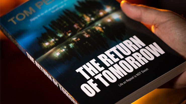 A colorful close-up of a person holding a book titled "The Return of Tomorrow" at Dreamland Magic.
