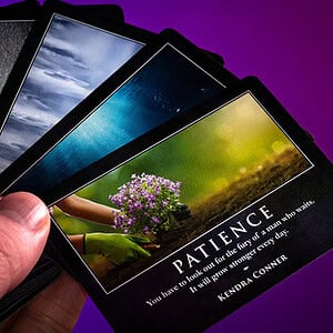 A person holding a deck of inspirational tarot cards with nature-themed images.