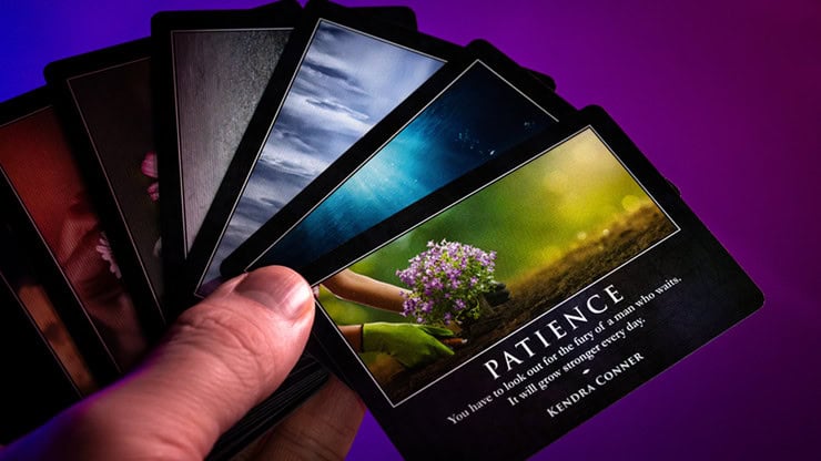 A person holding a deck of inspirational tarot cards with nature-themed images.