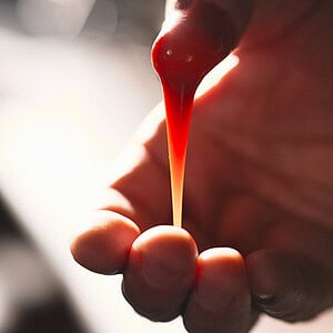 A colorful magic illusion with a red liquid drop falling from a magician’s hand.