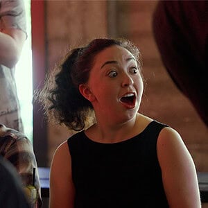 A woman with curly hair reacting excitedly at a magic show.