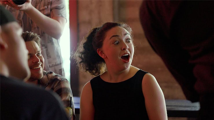 A woman with curly hair reacting excitedly at a magic show.