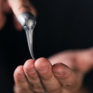 A person performing a magic trick with a silver spoon, demonstrating illusion and sleight of hand.