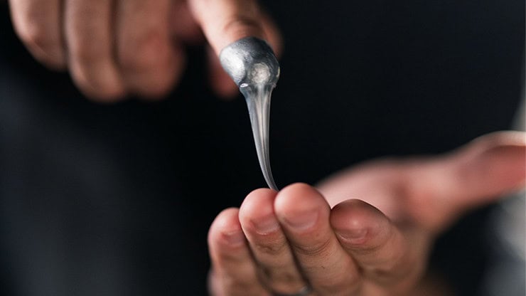 A person performing a magic trick with a silver spoon, demonstrating illusion and sleight of hand.