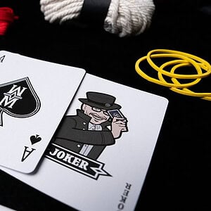 Magic playing cards with joker illustrations and accessories on a black background.
