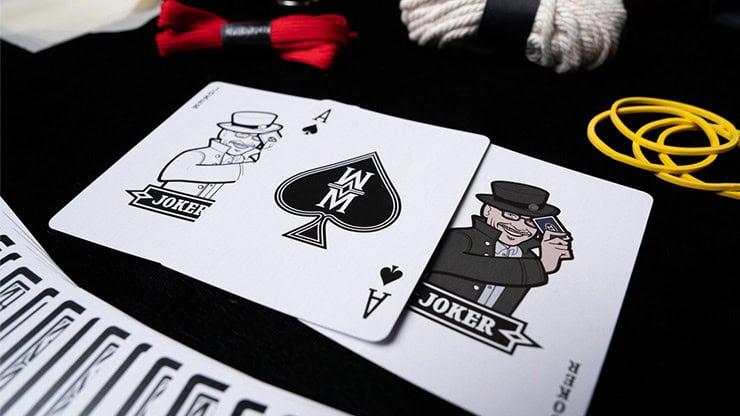 Magic playing cards with joker illustrations and accessories on a black background.