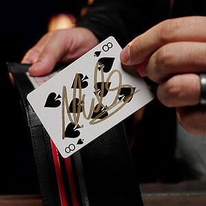 A magician's hand reveals a playing card from a deck, demonstrating a magic trick.