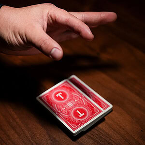 Close-up of a hand performing a card trick with a deck of red-backed cards.