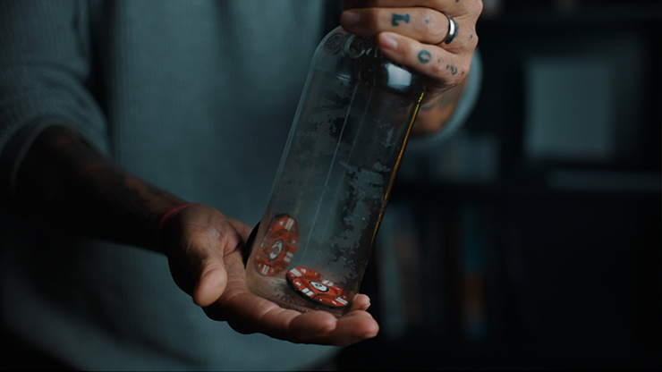 Close-up of a hand holding a glass bottle with dice inside, magic shop scene.