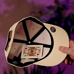 Close-up of a beige baseball cap with a colorful card inside the brim.