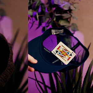 Close-up of a card being placed inside a black hat for a magic trick.