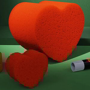Heart-shaped sponges with vibrant orange color, set against a green background with 
