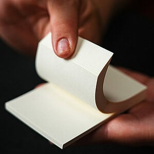 A magician's hand reveals a small, blank white card from a deck during a magic performance.