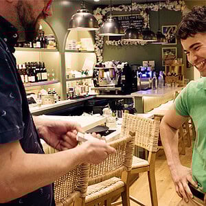 A colorful magic shop scene with a young man performing a trick for a customer.