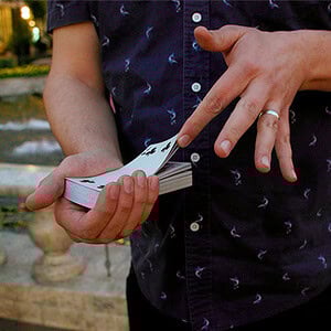 Close-up of a magician performing a card trick outdoors at night.