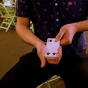 A colorful close-up of a person performing a card trick with a deck of playing cards.