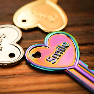 Colorful heart-shaped magic key with 'Smile' inscription on a wooden surface.