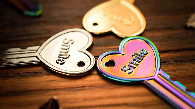 Colorful heart-shaped magic key with 'Smile' inscription on a wooden surface.