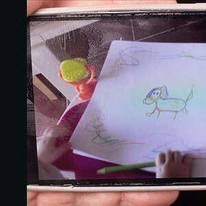 Child's colorful drawing of a dog on a spiral notebook page.