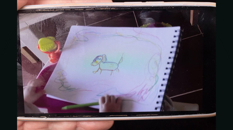 Child's colorful drawing of a dog on a spiral notebook page.