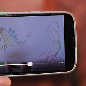 Child's drawing of a colorful dinosaur on a smartphone screen.