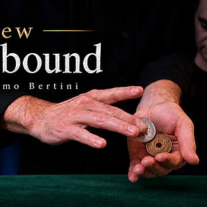Close-up of a magician's hands performing a coin trick with coins on a green table.