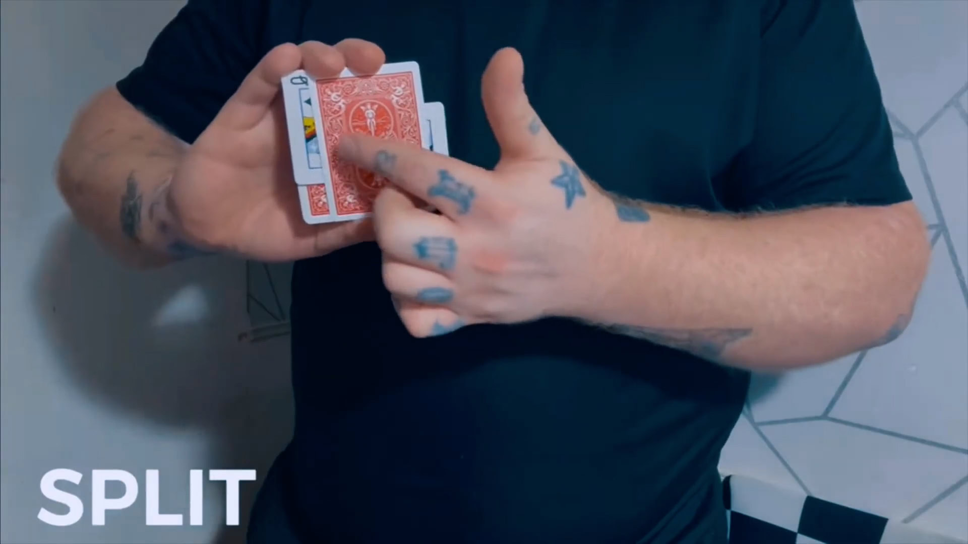 Close-up of a magician performing a card split trick with red playing cards.