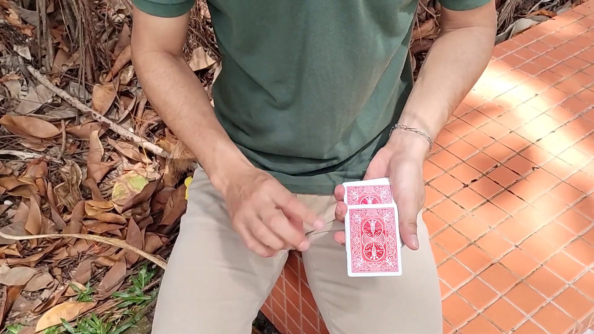 Close-up of a person performing an Ambitious card trick outdoors with autumn leaves.