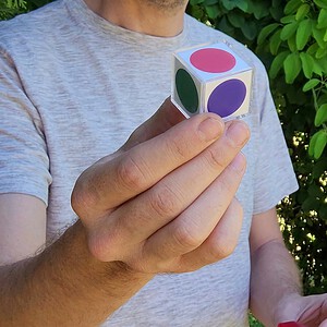 Color Vision magic trick - the color cube with colored dots held in the magician's hand during the demonstration