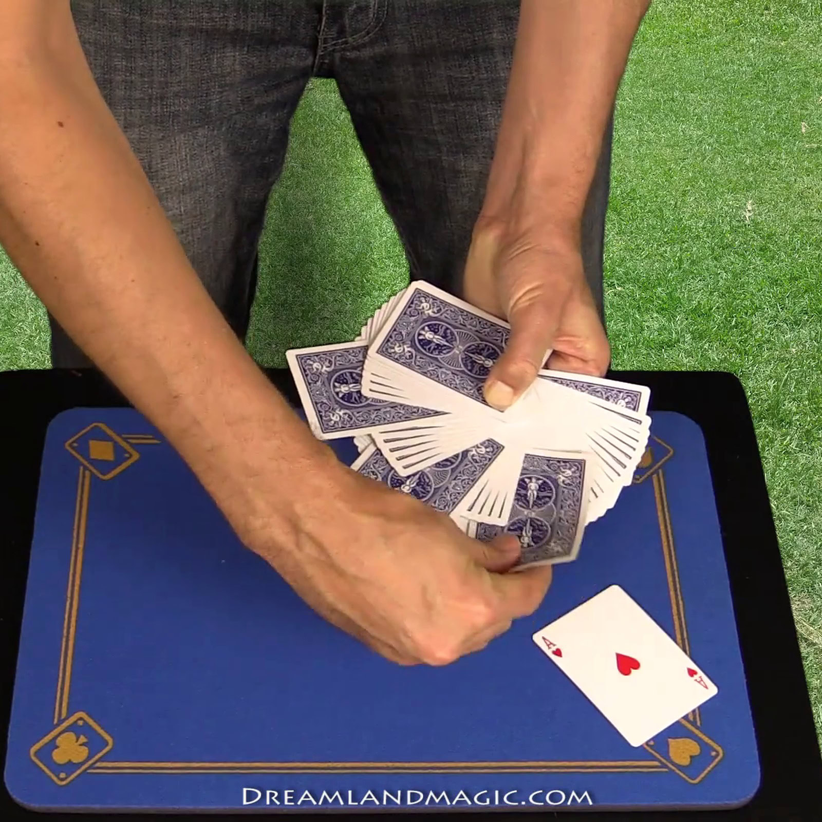 Performer shuffles and fans playing cards on a magic trick table.