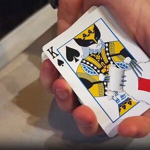 Hand holding a King of Spades playing card during a magic trick demonstration.
