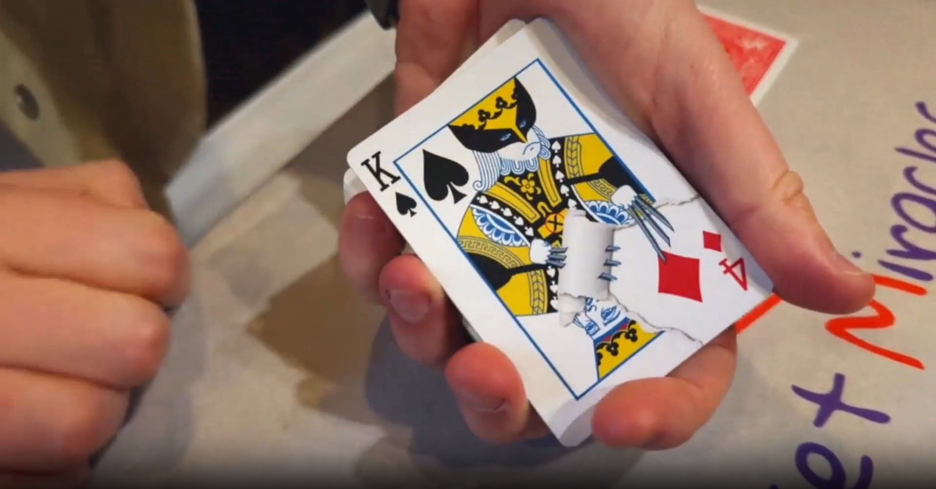 Hand holding a King of Spades playing card during a magic trick demonstration.