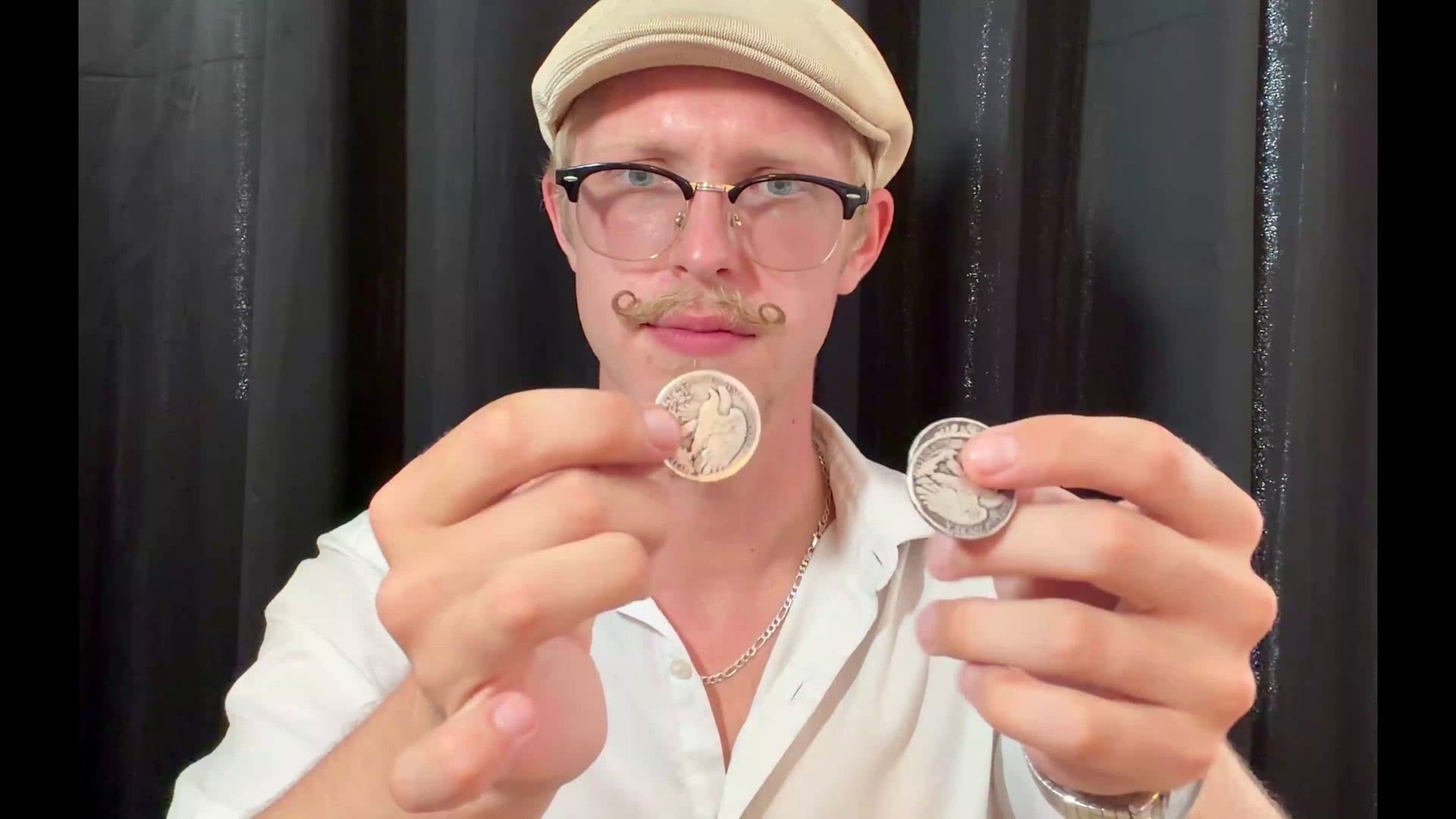 OneFly by Pieter Hofstra coin magic tutorial - magician displaying two silver coins
