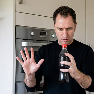 reKap by Richard Griffin magic trick - performer demonstrating the bottle cap effect in a kitchen