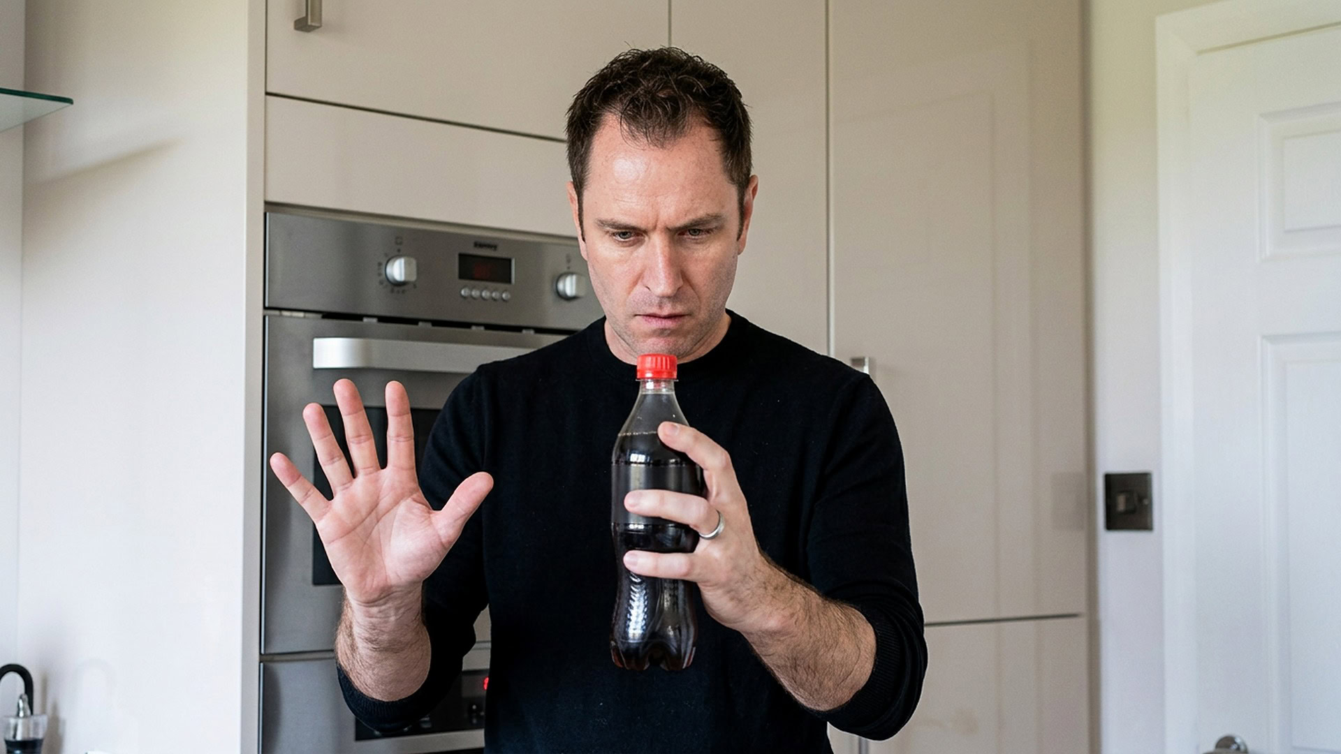 reKap by Richard Griffin magic trick - performer demonstrating the bottle cap effect in a kitchen